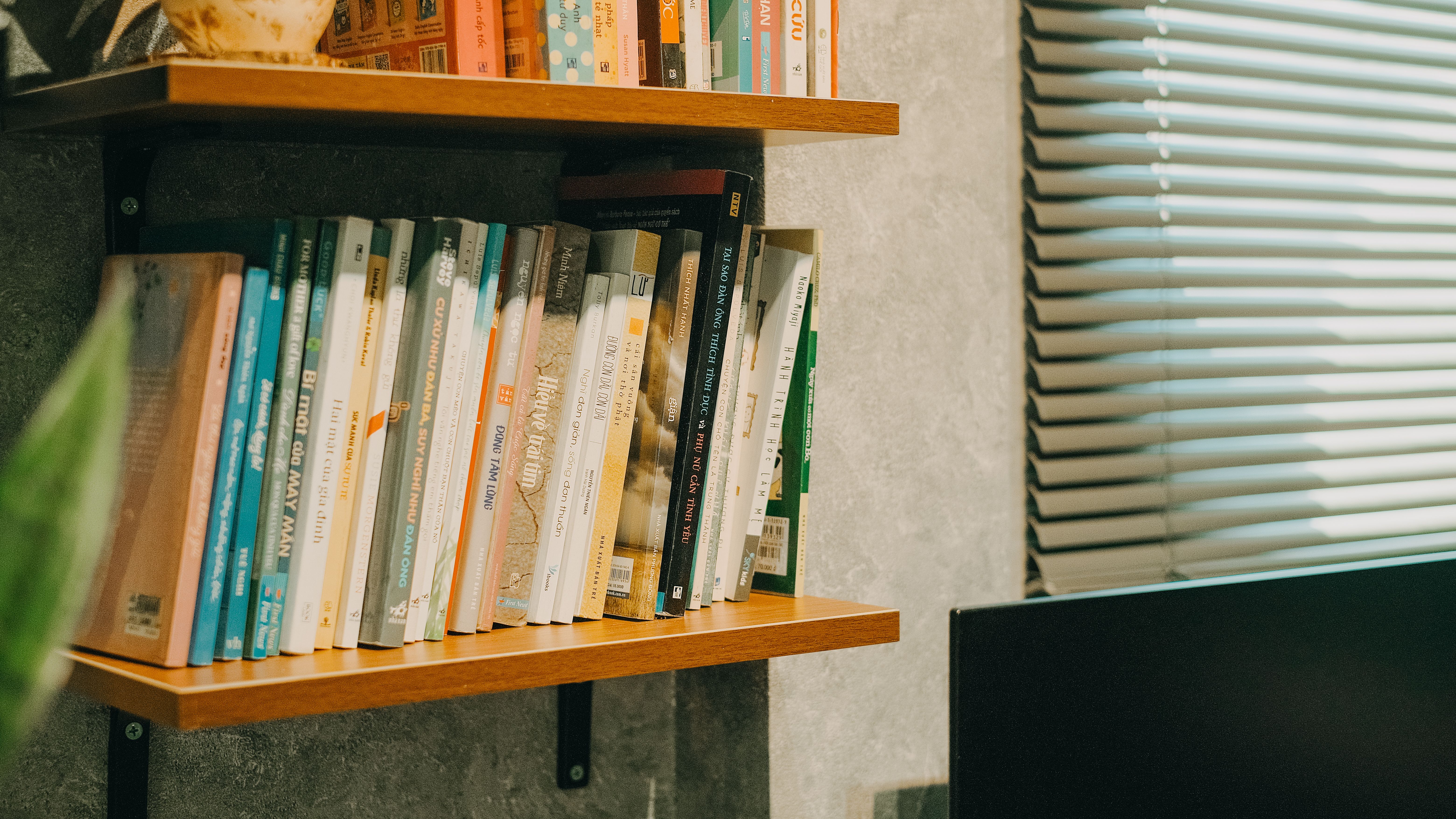 Wall-mounted corner bookcase with wooden shelves and ambient lighting