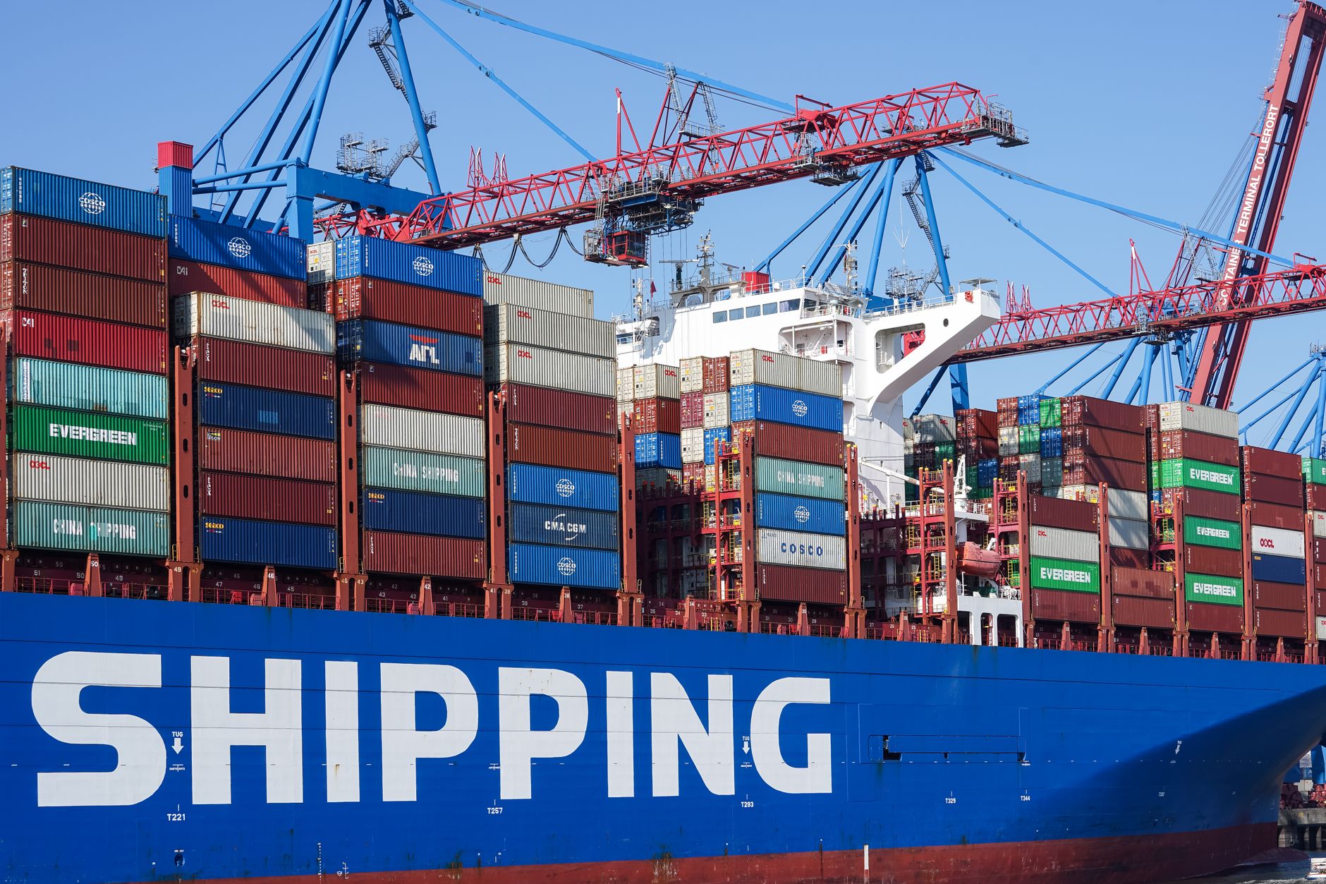 Large container ship docked at Hamburg port under cranes, showcasing global commerce and logistics.