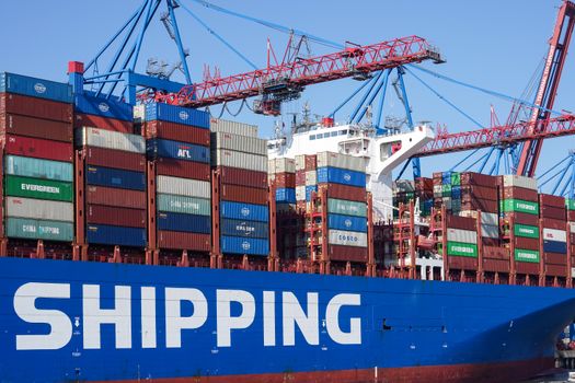 Large container ship docked at Hamburg port under cranes, showcasing global commerce and logistics.