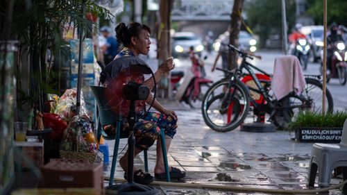 Free Capturing a casual moment of a woman relaxing on a bustling Hanoi street. Stock Photo