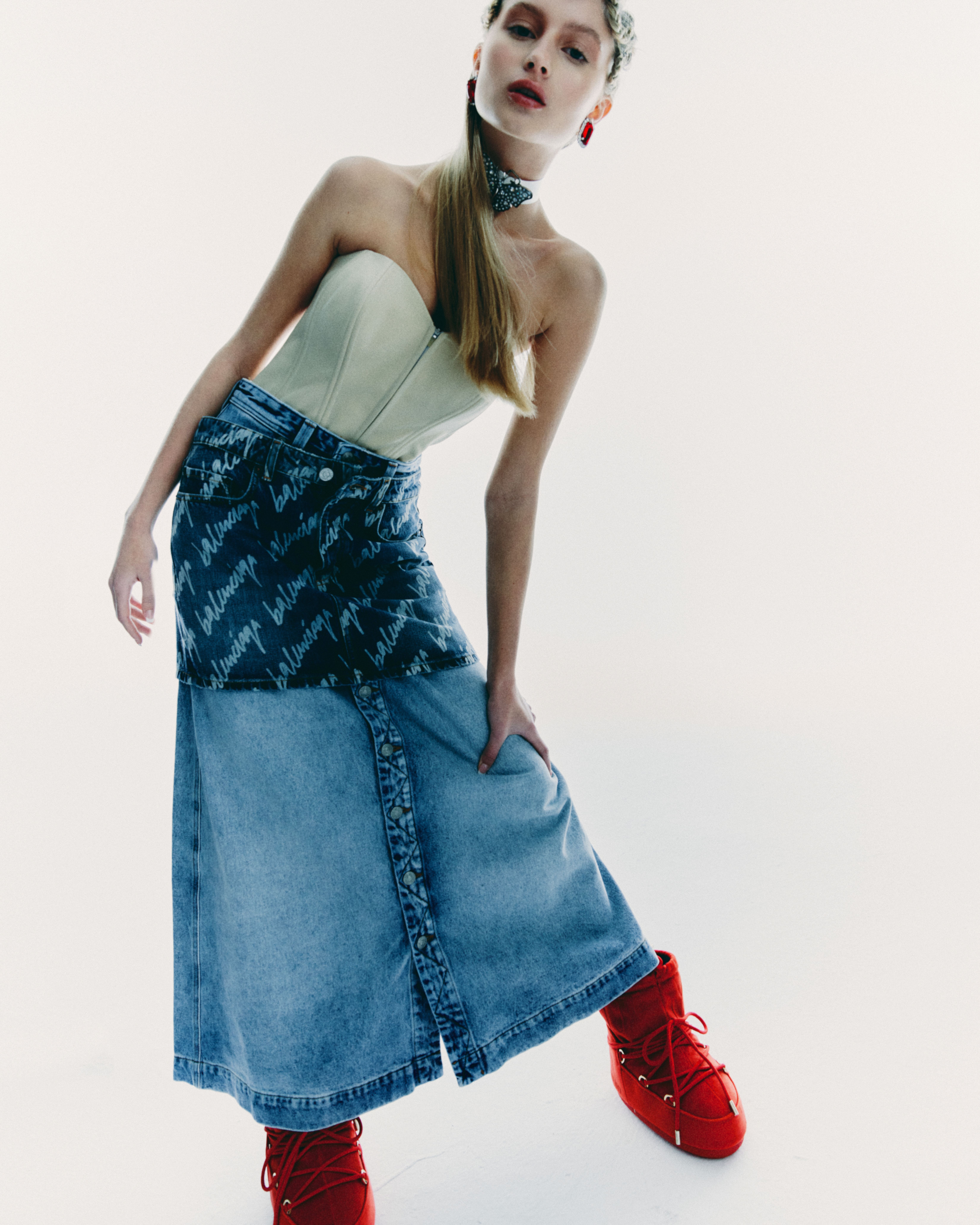 Contemporary fashion portrait featuring a model in a denim skirt and vibrant red boots, embodying modern trends.