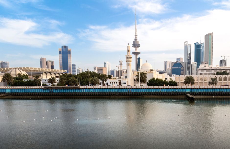 Scenic view of Kuwait City skyline featuring Liberation Tower and waterfront under a clear sky.
