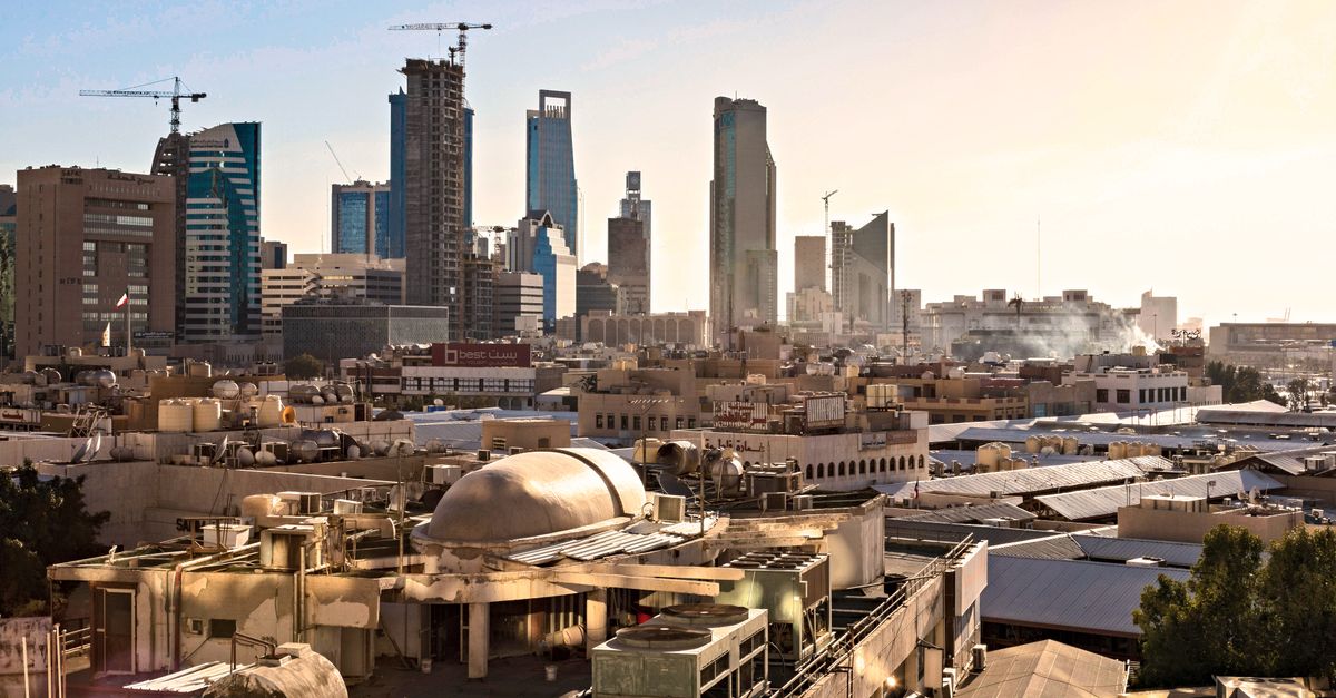 Skyline of Riyadh, Saudi Arabia featuring modern skyscrapers and construction cranes at sunset.