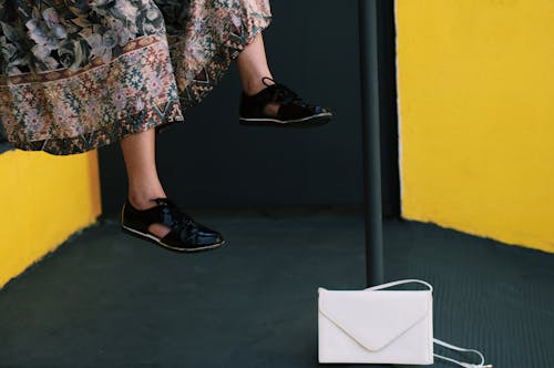 Free Woman in Long Skirt and Black Sneakers Sitting Beside White Handbag Stock Photo