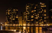 墨尔本的天际线上，现代建筑在夜间倒映于水面，明亮而清晰