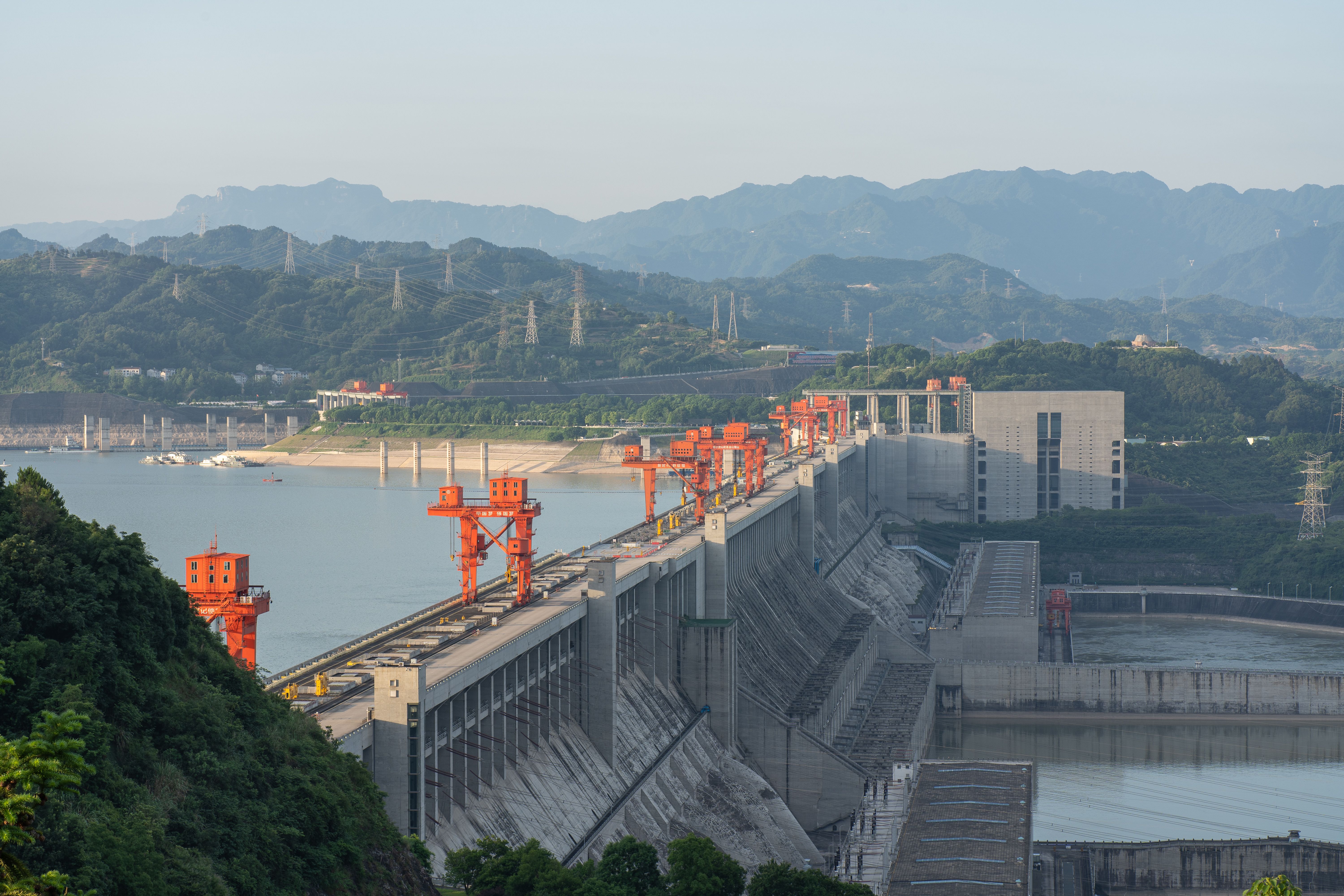A breathtaking aerial view of the Three Gorges Dam surrounded by mountains, emphasizing its massive scale.