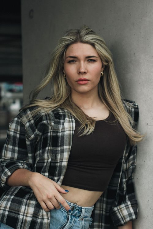 Free Blonde woman in plaid shirt and jeans poses confidently outdoors in Hamburg. Stock Photo