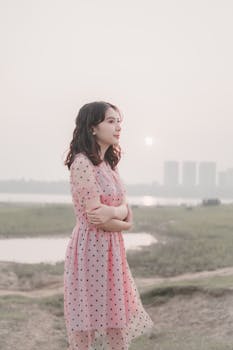 日落时分，一位身着粉色圆点连衣裙的女子在户外沉思，静享安宁