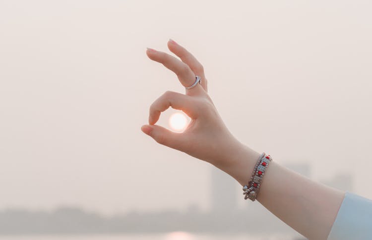 Crop Woman Showing Okay Gesture Touching Sun On Street