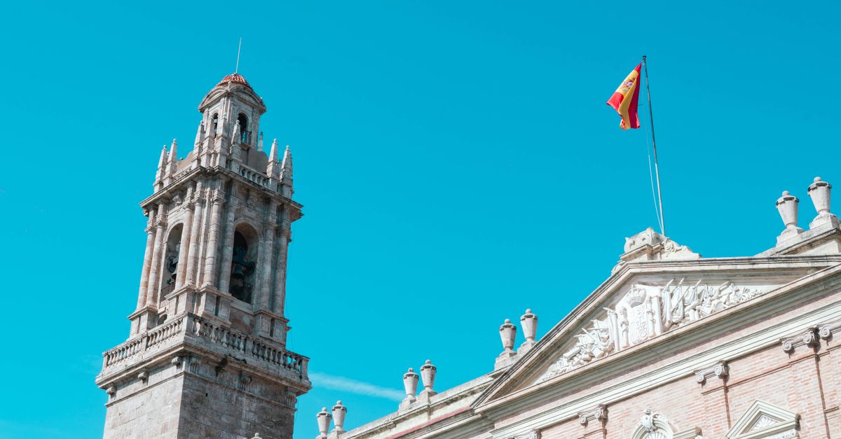 Preciosa fotografía de una histórica torre del reloj en Valencia, España, con un cielo azul despejado de fondo.