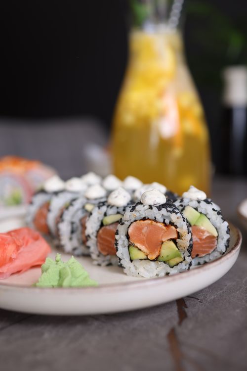 Free Close-up of sushi rolls with salmon, avocado, and cream cheese on a white plate. Stock Photo