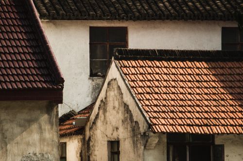 Free Sunlit view of traditional tiled roofs in a rustic village. Warm colors and textures emphasize architectural detail. Stock Photo