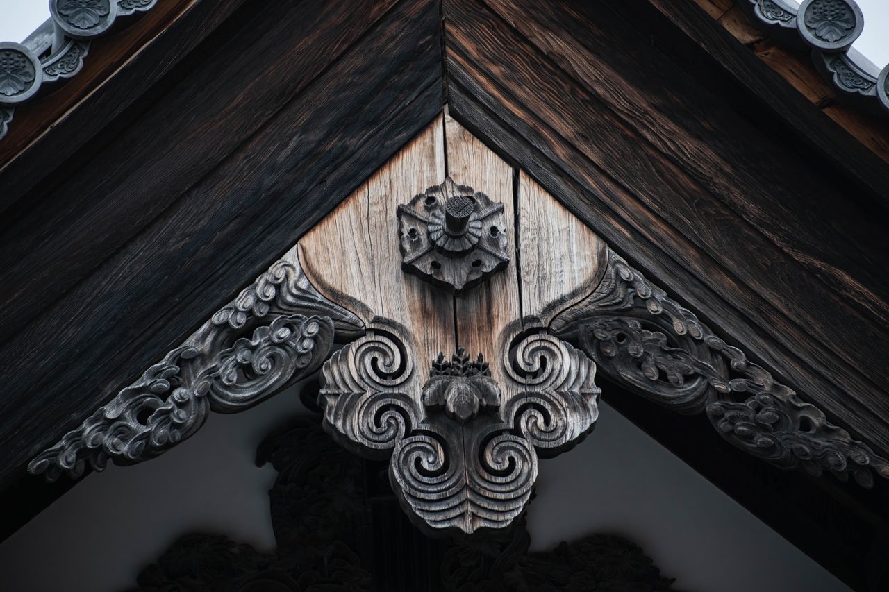 close up of ornate wooden carvings on a traditional temple roof showca