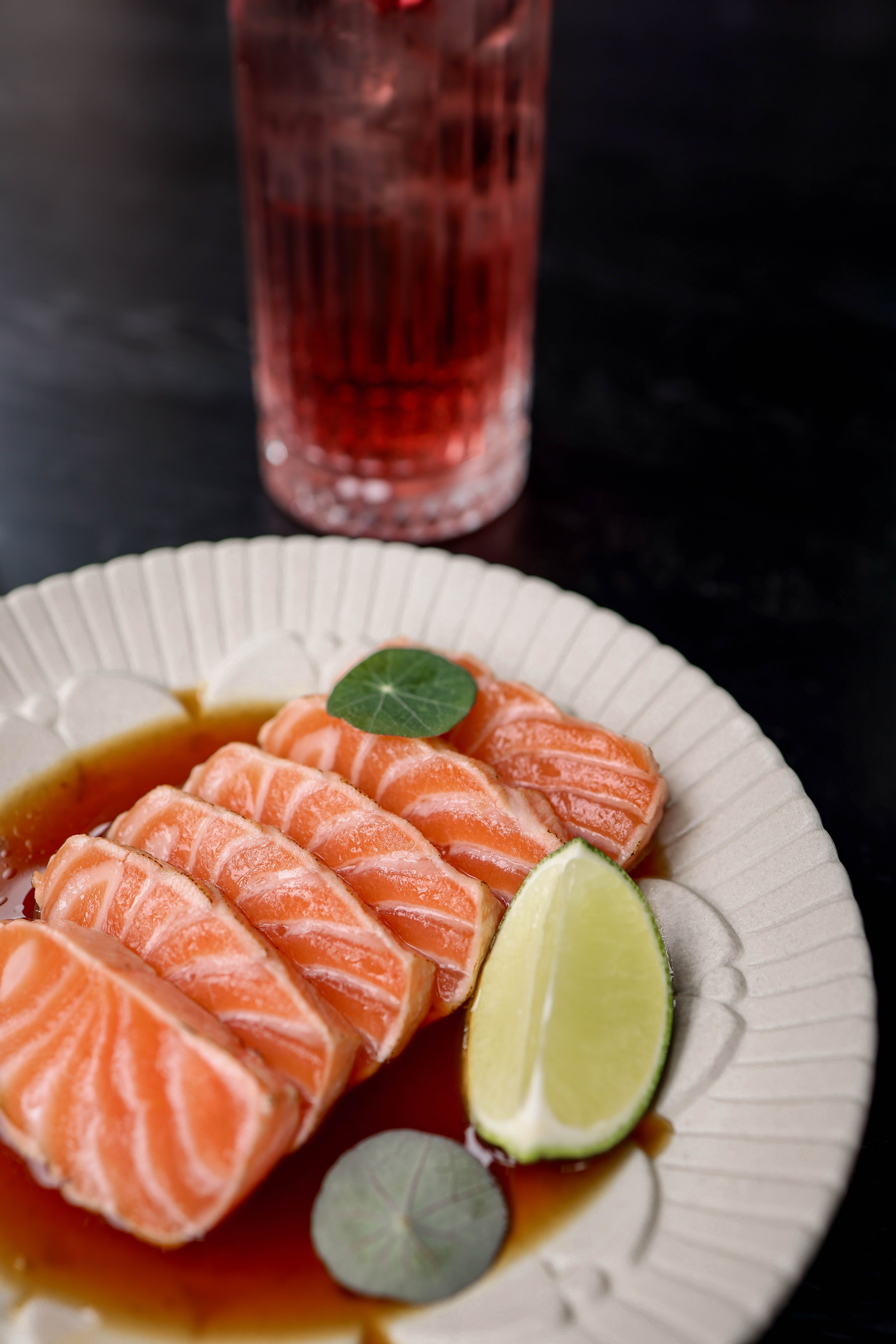 Freshly sliced salmon sashimi on a plate with soy sauce and lime wedge, perfect for seafood lovers.