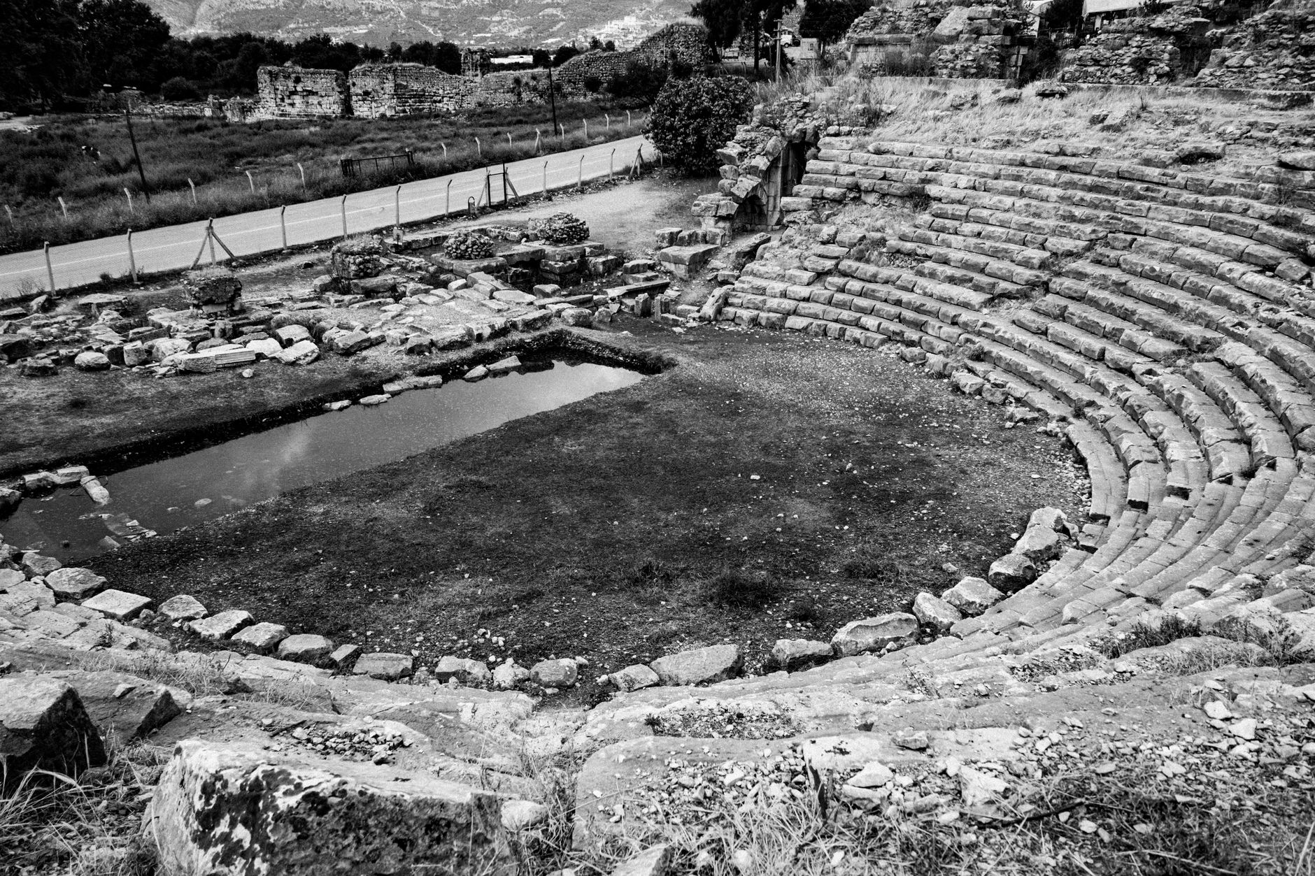 Monochrome view of a historic amphitheater with weathered stone seating in a deserted setting.