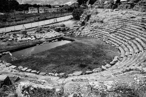 Free Monochrome view of a historic amphitheater with weathered stone seating in a deserted setting. Stock Photo