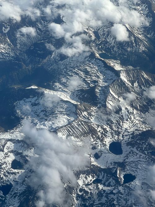 Free Dramatic aerial view of snow-covered mountains with scattered clouds. Stock Photo