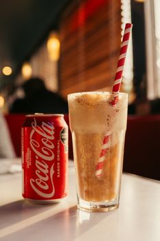 A chilled Coca-Cola float with a striped straw in a cozy Buenos Aires cafe, capturing an authentic dining experience.