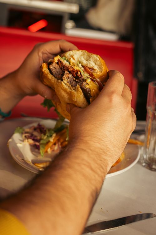 Free A person enjoying a delicious gourmet burger at a vibrant diner setting in Buenos Aires. Stock Photo