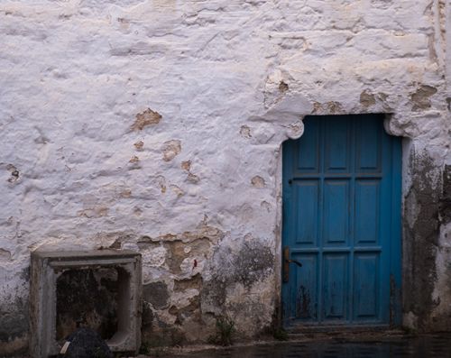 Free A rustic blue door set in a weathered white stone wall in Foça, İzmir, Türkiye. Stock Photo