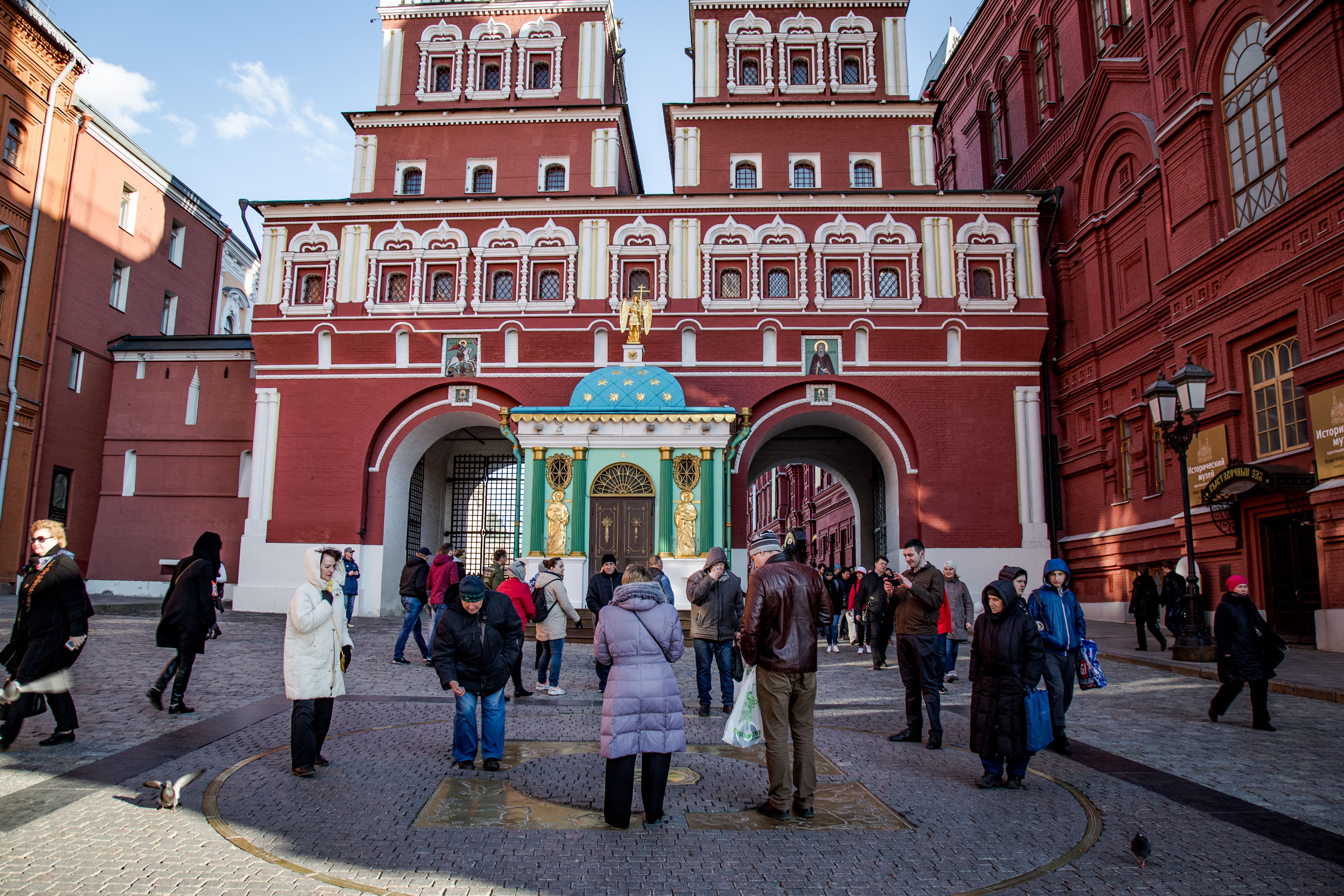 Lively scene at the Resurrection Gate in Moscow with people gathering amidst historic architecture.