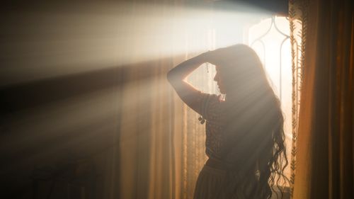 Free A captivating silhouette of a woman in a sunlit room with rays streaming through a window. Stock Photo
