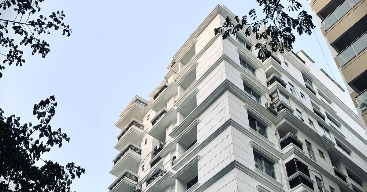 A low-angle shot of a modern high-rise building surrounded by tree branches.
