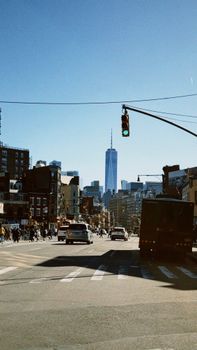 City street view with One World Trade Center in the background during a clear day in New York City.