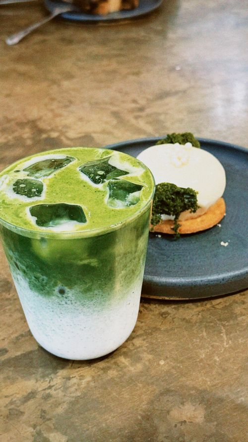 Free A refreshing iced matcha latte served with a decadent dessert on a rustic tabletop, perfect for a sweet treat break. Stock Photo