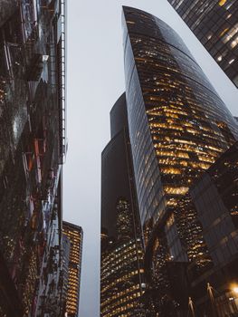 Low angle view of illuminated skyscrapers at night in an urban setting, showcasing modern architecture.