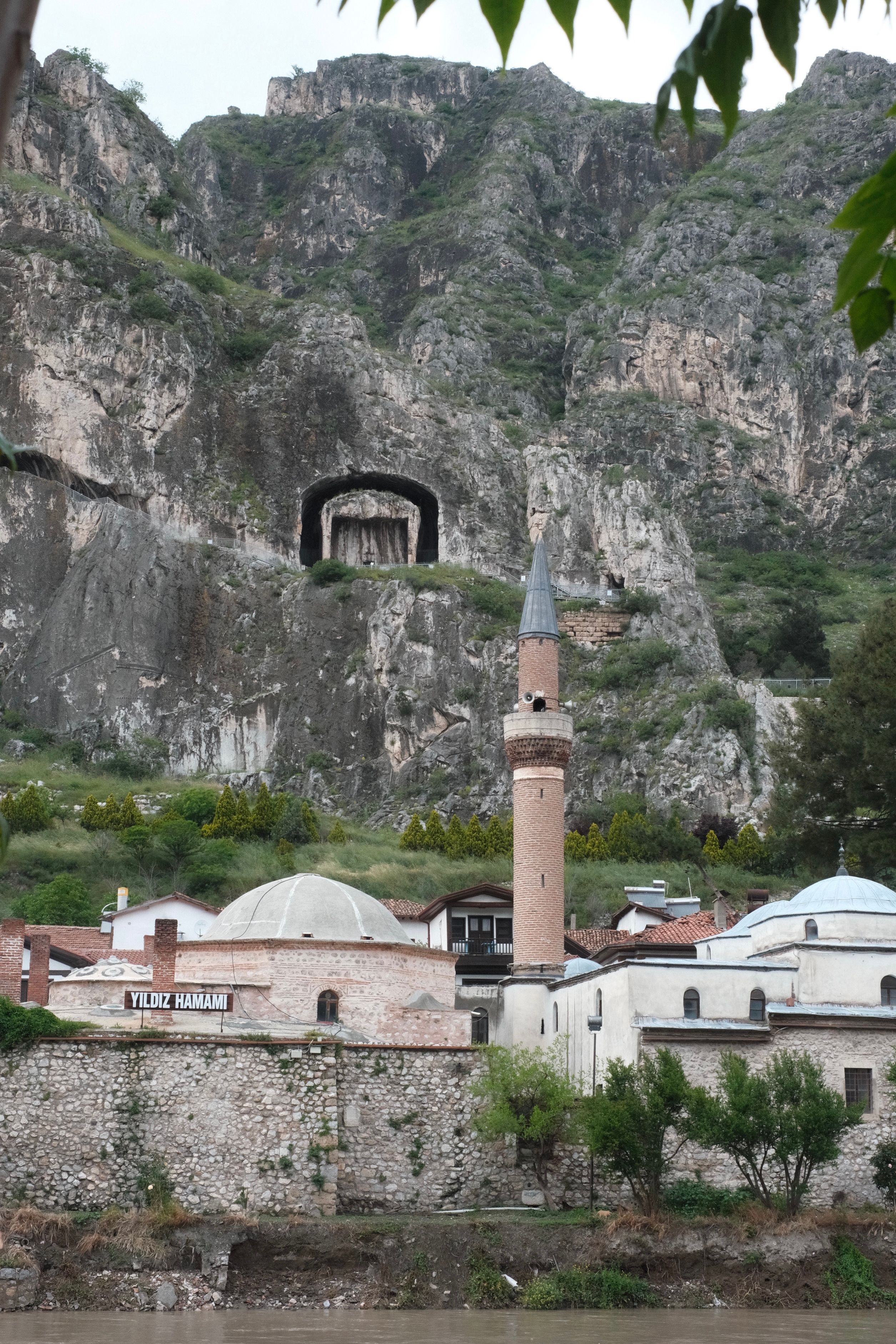A panoramic view of a historic Ottoman mosque nestled against the rocky cliffs of Amasya, Turkey.