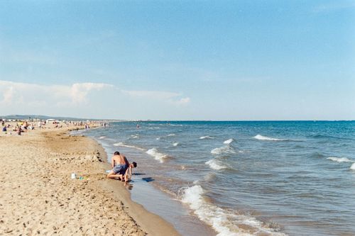 Free Relaxing beach scene at Gruissan, France, featuring people enjoying the sunny day by the sea. Stock Photo