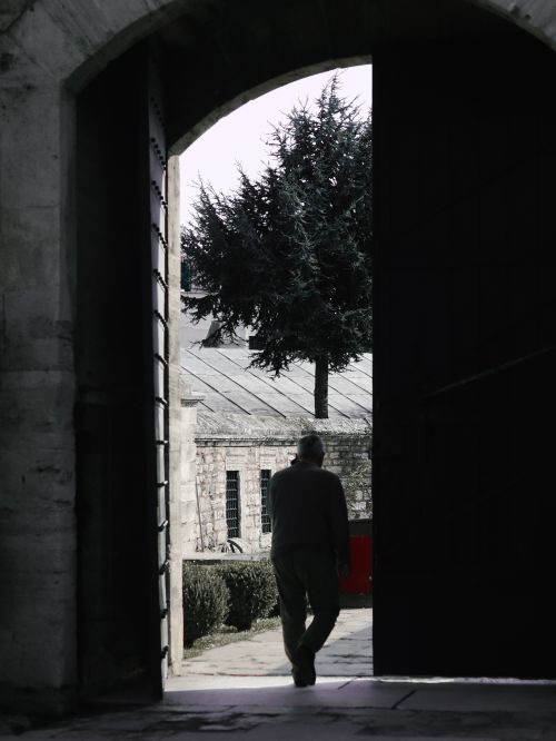 Free Silhouette of an adult male walking through an arched doorway in İstanbul, blurry silhouette of a tree in the background. Stock Photo