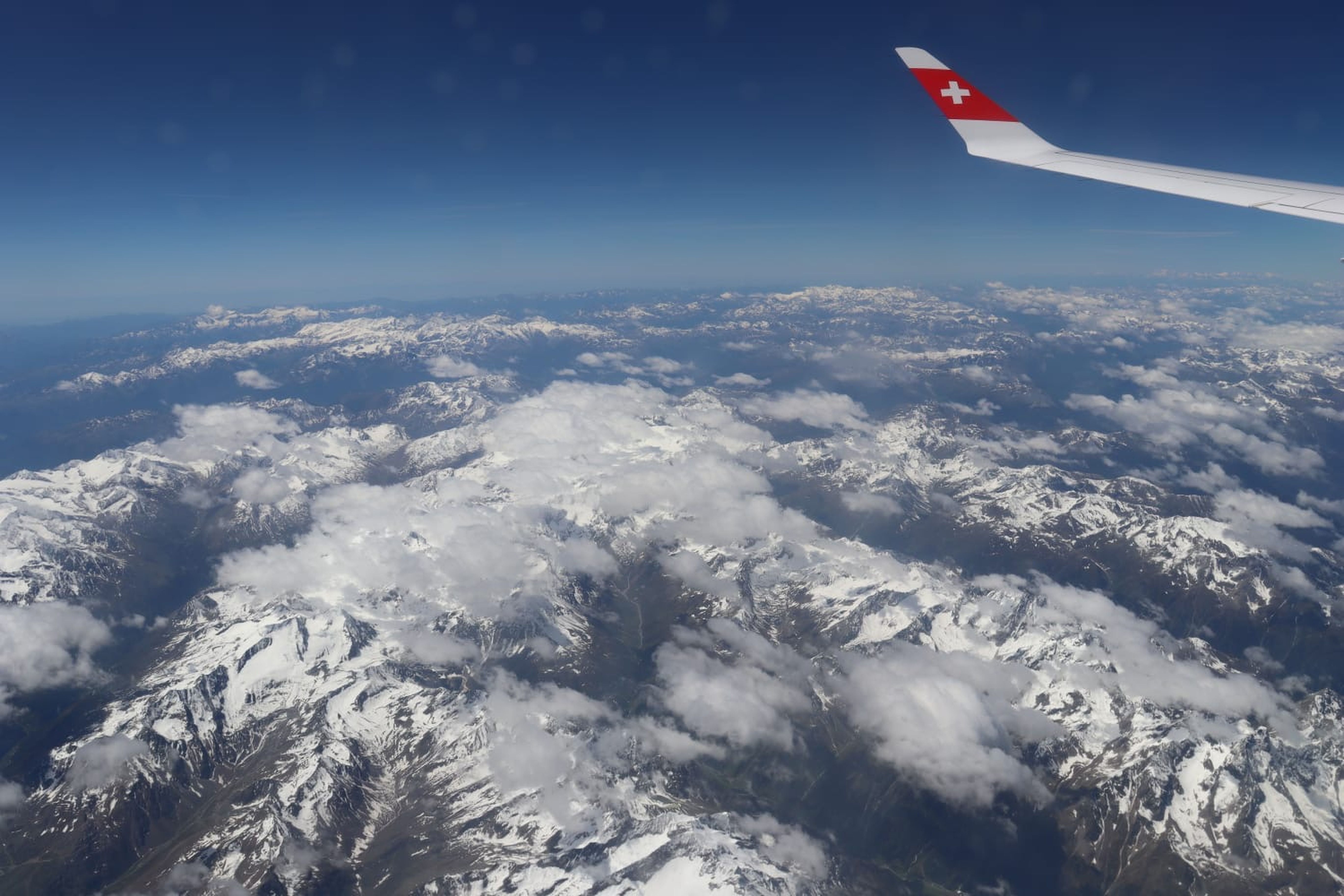 Stunning aerial view of snow-covered Swiss Alps with airplane wing.