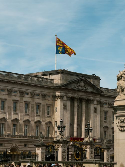 Free Buckingham Palace facade with royal flag, capturing iconic British architecture and history. Stock Photo