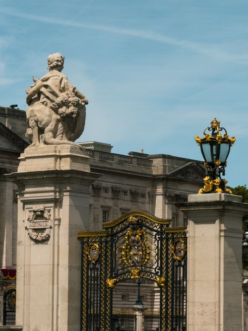 Free Elegant sculpture and ornate gates at Buckingham Palace, London, against a clear sky. Stock Photo