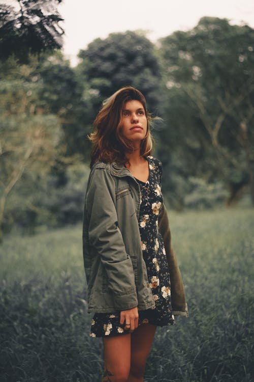 Casual ethnic woman standing pensively in woods