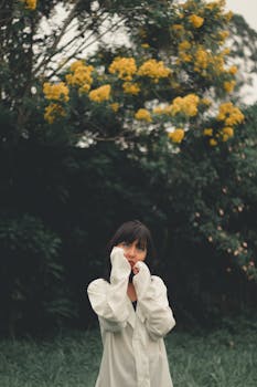 一位穿着白衬衫的女人，在宁静的自然环境中沉思，背景是黄色的花朵