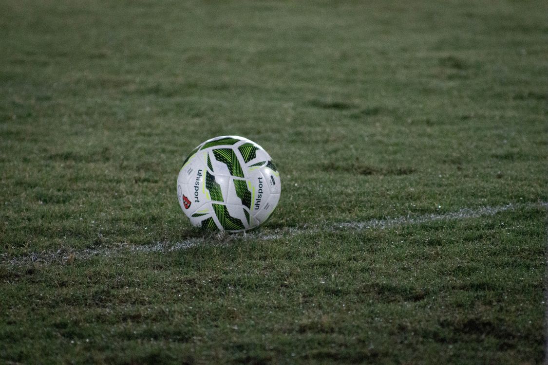 Soccer ball resting on grass under stadium lights at night