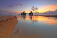 日出时分，宁静的海滩上，平静的海水映照着鲜艳的天空色彩