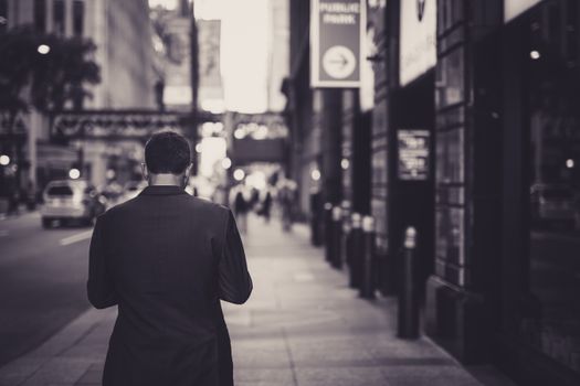 Man in a suit walking down a city street in a lonely, urban setting.
