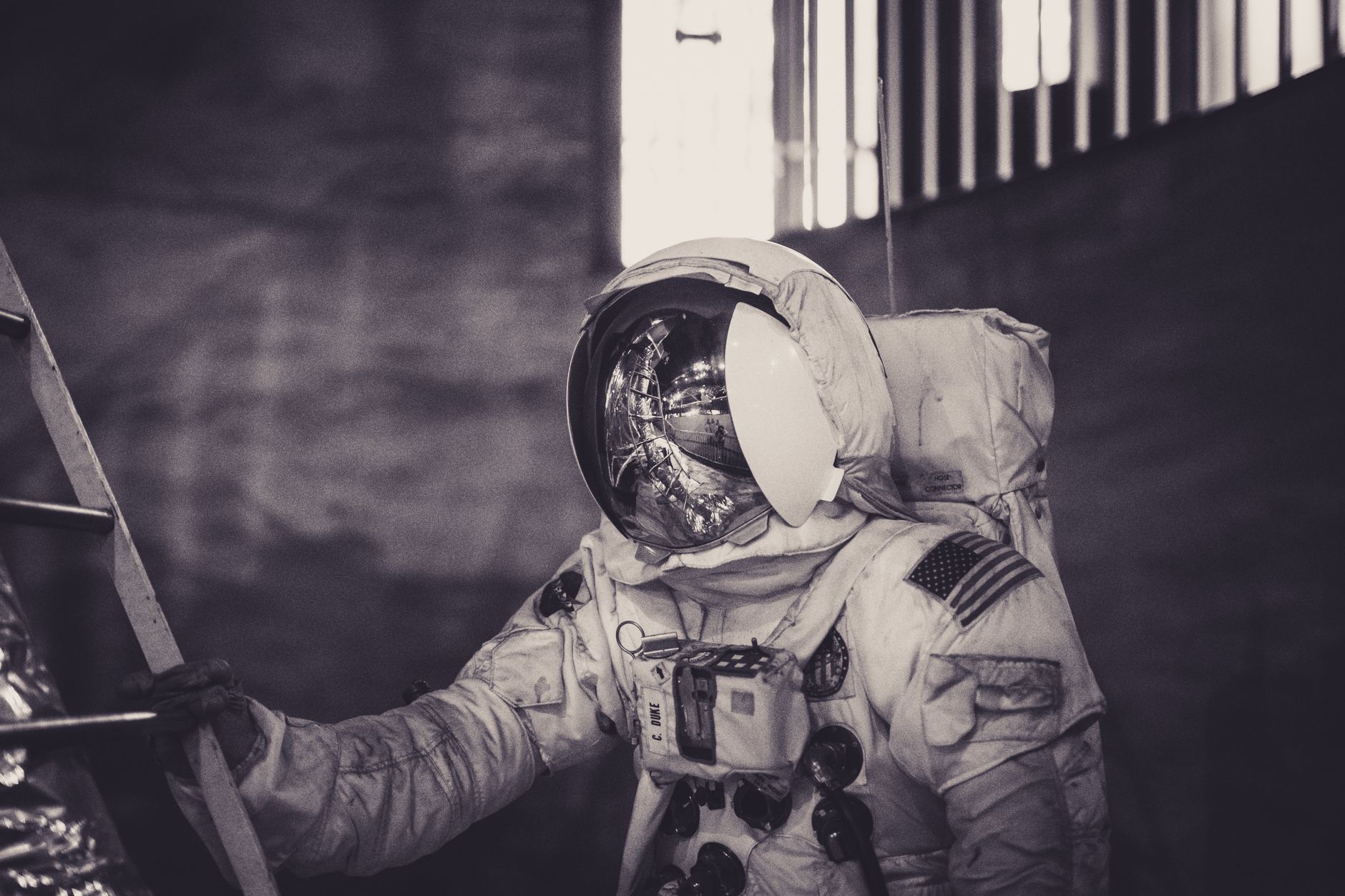 Astronaut in spacesuit climbing ladder inside a dark setting. — free online jigsaw puzzle on JigsawPuzzlesFreeOnline.org