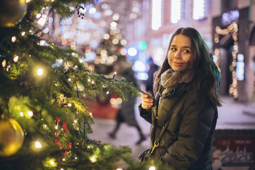 A young woman in a winter jacket enjoys festive decorations on a lively city street.