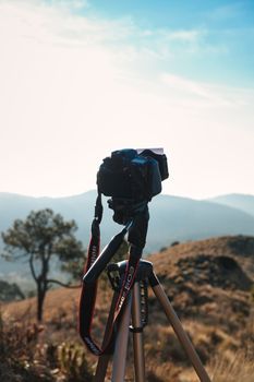 Camera setup on tripod in scenic hilly landscape, perfect for outdoor photography or videography enthusiasts.