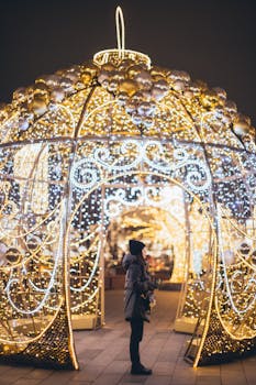 身着冬装的妇女观看着装饰有灯光的节日拱门