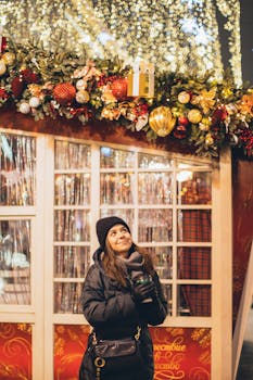 一位面带微笑的女人快乐地站在节日的圣诞彩灯和装饰品下，沉浸在节日气氛中