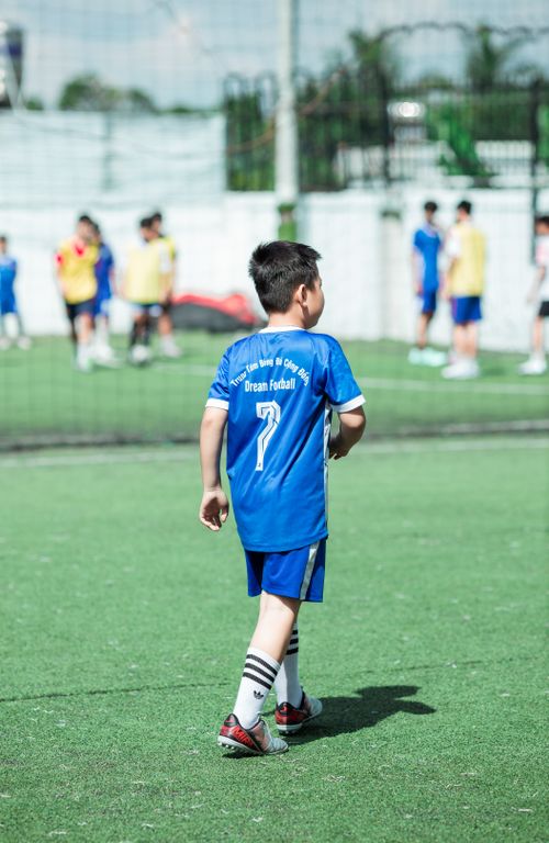 Free Young boys playing a soccer match on a field, wearing blue uniforms under sunny weather. Stock Photo
