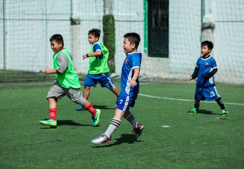 Free Young boys playing soccer on a sunny day in Kon Tum, Vietnam, highlighting teamwork and outdoor fun. Stock Photo