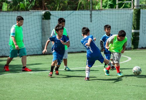 Free Energetic group of kids playing soccer outdoors on a bright day in Kon Tum, Vietnam. Stock Photo