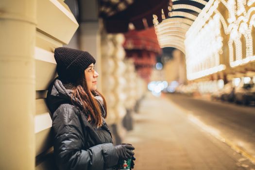 冬夜里，一个女人戴着无檐帽，在城市的灯光背景中沉思